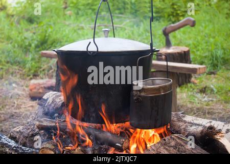 Due bollitori da turismo fumati sopra il fuoco del campo. Processo di cottura sulla natura Foto Stock