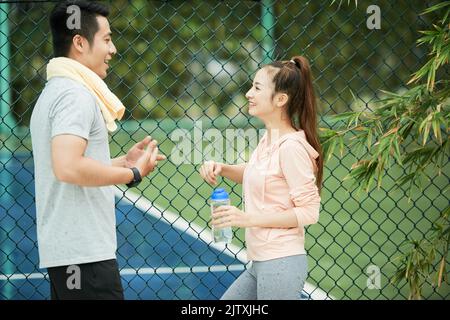 Giovane coppia sportiva che chiacchiera e beve acqua dopo l'allenamento Foto Stock