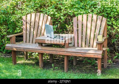 Home office nel proprio giardino con panchina da giardino e il computer portatile Foto Stock