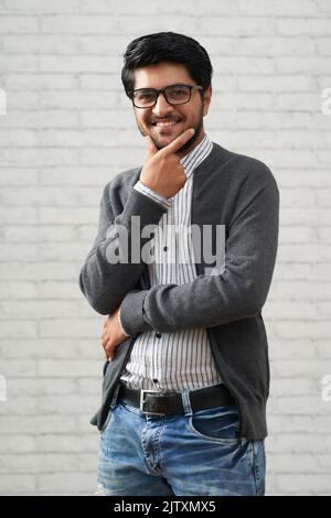 Giovane uomo indiano sorridente in abiti casual guardando la macchina fotografica Foto Stock