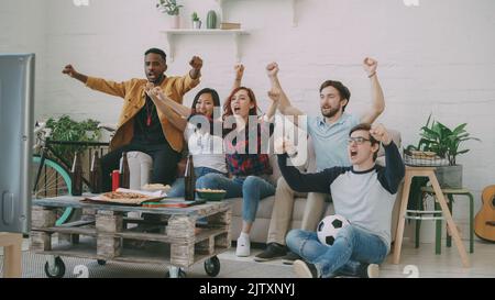 Gruppo di amici felici guardando gioco di sport in TV a casa al coperto. Sono felici della loro squadra preferita vincere la concorrenza Foto Stock