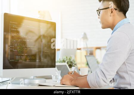 Giovane manager seduto al tavolo e lavorando al computer in ufficio Foto Stock