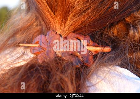 Capelli rossi di una donna con una clip in legno a forma di geco Foto Stock