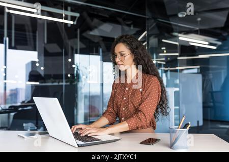 Bella donna indiana programmatore sviluppatore web concentrato e sicuro di lavorare sul computer portatile scrittura codice programmazione lavoro donna lavoratore in ufficio moderno che lavora in abiti casual. Foto Stock