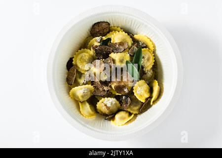 Ravioli italiani con burro, parmigiano e tartufo sul tavolo bianco in una scatola per la consegna Foto Stock