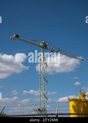 Grande gru industriale con scale in ferro e cielo nuvoloso blu Foto Stock
