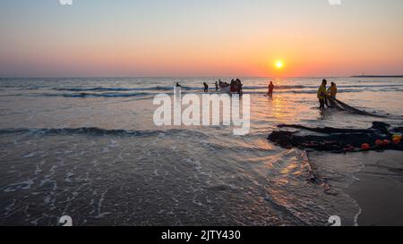 I pescatori si preparano per le reti da pesca della barca a remi sulle silhouette del litorale della spiaggia contro l'orizzonte mattutino l'alba dell'oceano un paesaggio di lifestyle. Foto Stock