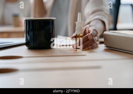 Primo piano delle gocce da naso e tazza in ufficio Foto Stock