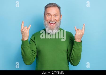 Foto dell'eccitata uomo di mezza età che fa una performance punk simbolo rock isolato su sfondo di colore blu Foto Stock