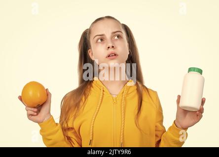 teen girl scegliere tra frutta d'arancia e pillola di vitamina in barattolo, additivi alimentari. Foto Stock