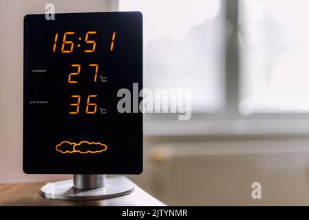 Caldo giorno d'estate. Le temperature elevate vengono visualizzate sul display della stazione meteo domestica. Il sole splende attraverso la finestra. Foto Stock