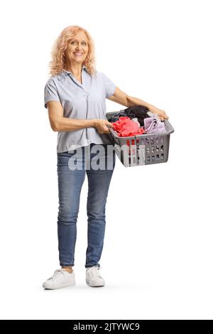 Ritratto a tutta lunghezza di una donna matura che tiene un cesto di bucato con vestiti isolati su sfondo bianco Foto Stock