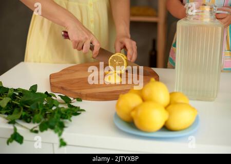 donna fare la limonata fatta in casa con limoni gialli freschi e menta verde. poco profonda di campo primo piano foto Foto Stock