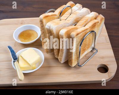 Prima colazione brindisi in rack con burro e marmellata sfondo tavolo in legno Foto Stock