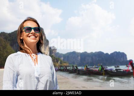 donna sorridente in occhiali da sole sulla spiaggia tropicale Foto Stock