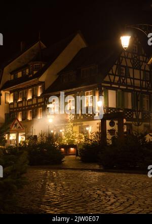 Gengenbach, Germania - 13 dicembre 2020: Ristorante in un edificio ad angolo a graticcio illuminato di notte a Gengenbach, Germania. Foto Stock