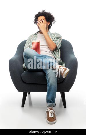 uomo con popcorn che guarda il film seduto in sedia Foto Stock