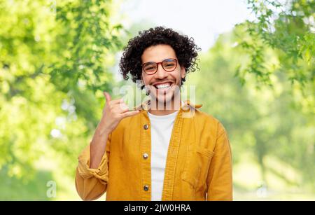 uomo che fa un gesto del telefono su sfondo naturale Foto Stock