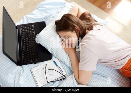 ragazza studentesca stanca con un notebook che dorme a casa Foto Stock