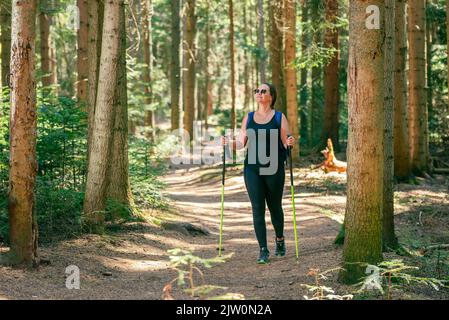 Donna cammina attraverso la foresta su un sentiero ben calpestato. Il concetto di una vita sana, godendo e giocando sport in natura Foto Stock
