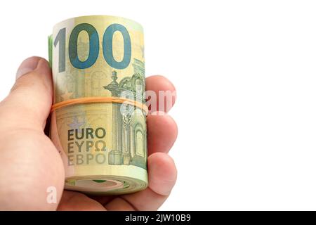 Denaro in mano isolato su bianco. La mano contiene un rotolo di 100 banconote in euro. Banconote in euro arrotolate in mano isolate su sfondo bianco. Il Foto Stock