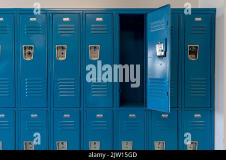 Armadietti in metallo blu lungo un corridoio non descritto in una scuola superiore tipica degli Stati Uniti. Nessuna informazione identificabile inclusa e nessuno nella sala. Foto Stock