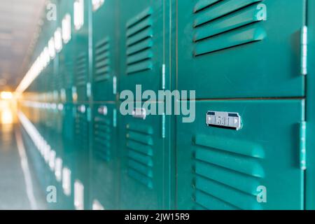 Armadietti di metallo verde lungo un corridoio non descritto in una scuola superiore tipica degli Stati Uniti. Nessuna informazione identificabile inclusa e nessuno nella sala. Foto Stock