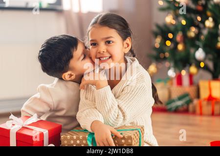 ragazzo baciare sorella con i regali di natale a casa Foto Stock