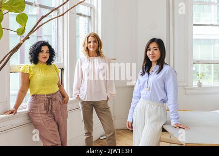 Ritratto di donne d'affari sorridenti in piedi in ufficio creativo Foto Stock