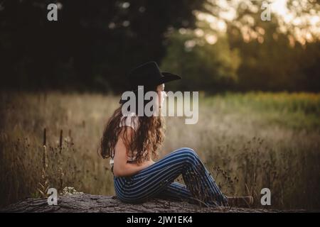 Cowgirl in campo guardando oltre pascolo Foto Stock