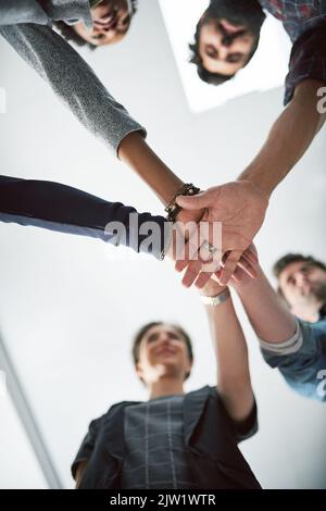 L'unità è il segreto del loro successo: Un gruppo di imprenditori creativi che si accatastano le mani l'una sull'altra. Foto Stock