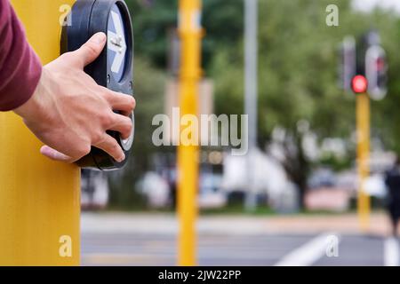 Attraversare sempre con cura. Una mano di mans premendo il pulsante di incrocio in corrispondenza di un incrocio. Foto Stock