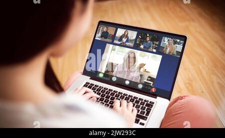 Vista posteriore della donna che ha una videoconferenza sul computer portatile a casa Foto Stock