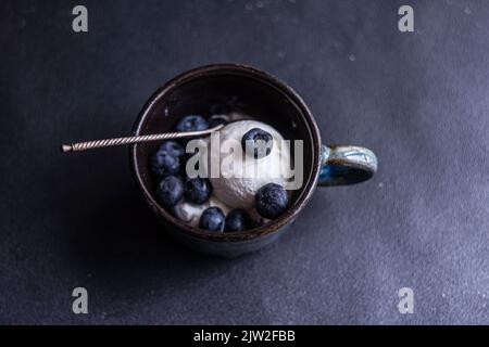 Da sopra ciotola piena di deliziosi mirtilli maturi posti su sfondo nero Foto Stock