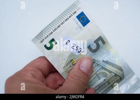 Banconota da cinque euro con prezzo da 2 euro a 5 cent. Attenzione selettiva all'etichetta. Inflazione in Europa, iperinflazione, svalutazione del concetto di moneta fiat. Foto Stock