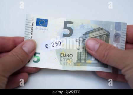 Banconota da cinque euro con prezzo da 2 euro a 5 cent. Attenzione selettiva all'etichetta. Inflazione in Europa, iperinflazione, svalutazione del concetto di moneta fiat. Foto Stock