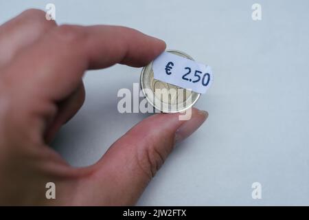 Mano con due monete da 2 euro 5 centesimi. Attenzione selettiva all'etichetta. Inflazione in Europa, iperinflazione. Foto Stock