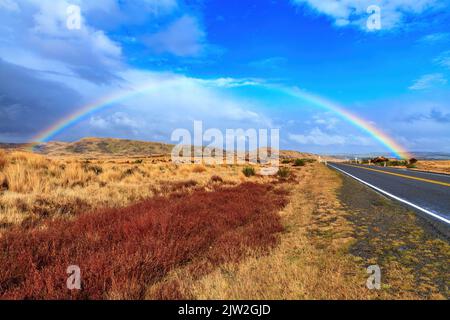 Un arcobaleno sulla Desert Road nell'altopiano vulcanico dell'Isola del Nord della Nuova Zelanda Foto Stock