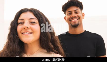 Vista frontale di una coppia multirazziale sorridente che guarda la telecamera Foto Stock