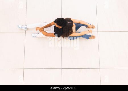Da sopra giovani coppie seduti a terra di nuovo a indietro rilassarsi in città Foto Stock
