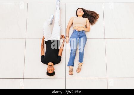 Vista ad alto angolo di una giovane ed elegante coppia sdraiata al piano Foto Stock