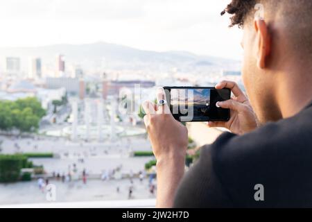 Primo piano di un giovane che fotografa la città attraverso lo smartphone Foto Stock