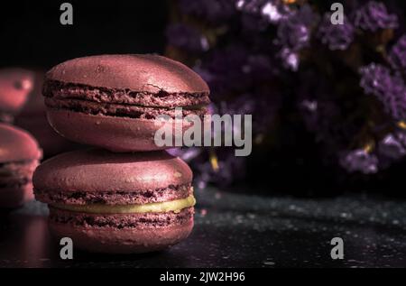 Coppia di deliziosi amaretti dolci di colore viola impilati insieme su un tavolo illuminato al sole al mattino Foto Stock