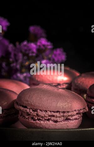 Deliziosi amaretti dolci di colore viola insieme sul tavolo illuminato al sole al mattino Foto Stock