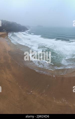 Dall'alto scenario pittoresco di roccioso scoscesa spiaggia bagnata dal mare ondeggiante sotto nebbia cielo nuvoloso a Elizondo in Navarra, Spagna Foto Stock