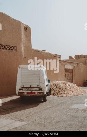 Furgone bianco parcheggiato vicino a casa medievale scoscesa situato contro cielo blu nuvoloso su strada dell'Iran, il giorno di sole estate Foto Stock