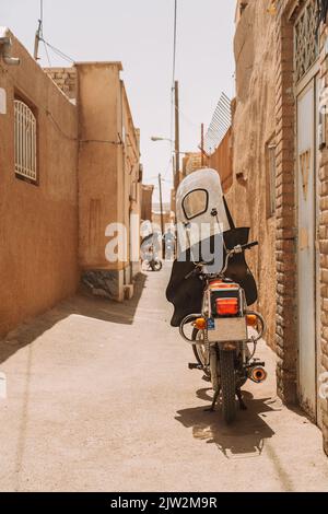 Moto parcheggiato sul percorso tra case residenziali di agrida anziane situate su strada dell'Iran, il giorno di sole estate in città Foto Stock