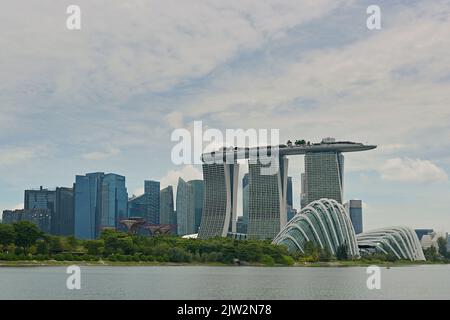 Vista del resort integrato Marina Bay Sands e dei giardini presso il parco Bay dall'altra parte del bacino idrico, con il Centro finanziario Marina Bay sullo sfondo Foto Stock