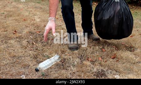Mano e piedi di persona che raccoglie figliata in un parco Foto Stock