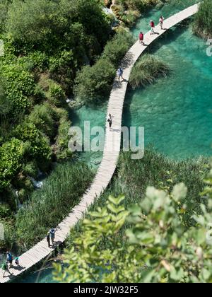 Vista aerea dei turisti che camminano a bordo di una passeggiata su una delle numerose piscine e laghi del Parco Nazionale dei Laghi di Plitvice, Croazia, Europa. Foto Stock
